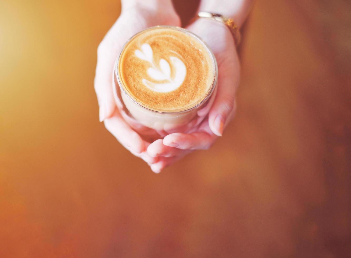 Close up hands of barista woman holding cup of hot cappuccino coffee in the cafe, copy space photo