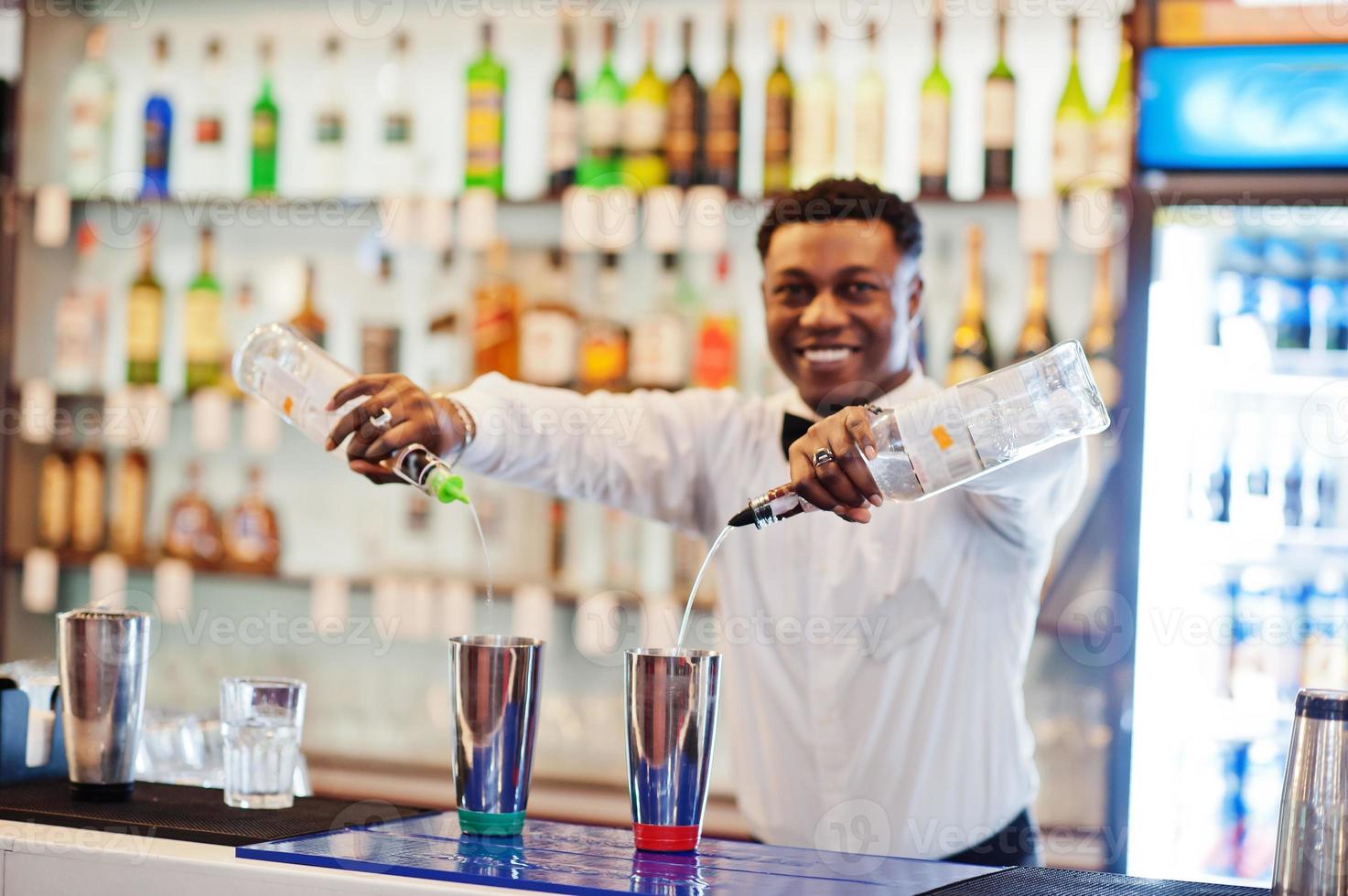 camarero afroamericano trabajando detrás del bar de cócteles. preparación de bebidas alcohólicas. foto