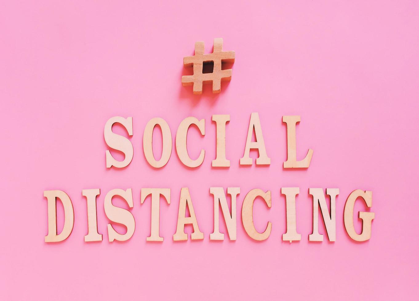 Flat lay of alphabet wooden letter about hashtag social distancing concept on bright pink background, prevent the spread of pandemic Covid-19 and Coronavirus, photo