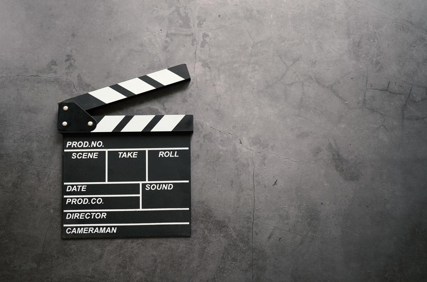 Empty clapperboard in flat lay style on dark stone background with copy space, entertainment and cinema industry photo