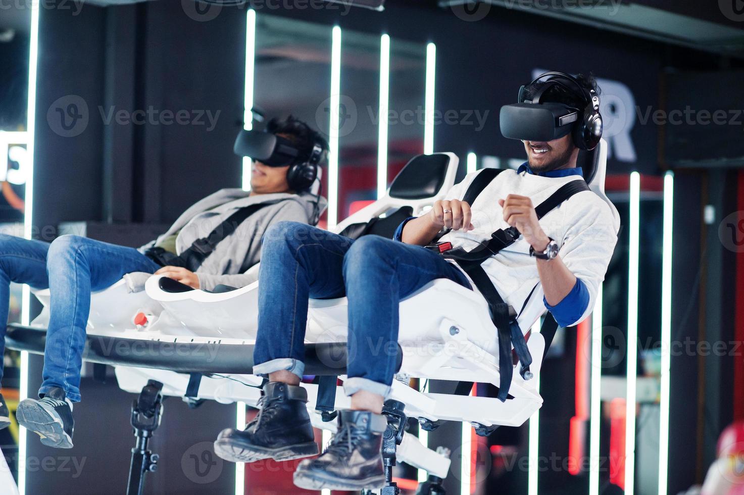Two young indian people having fun with a new technology of a vr headset at virtual reality simulator. photo