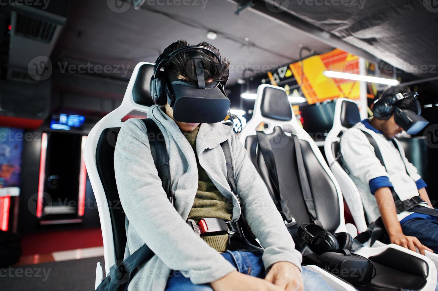Two young indian people having fun with a new technology of a vr headset at virtual reality simulator. photo
