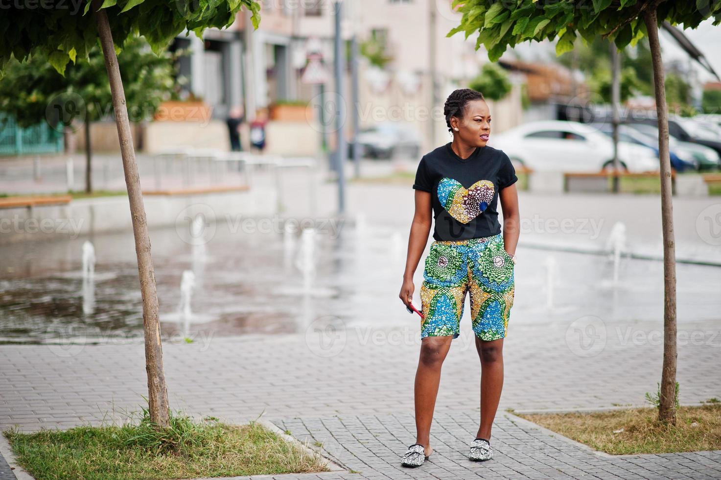 Young african american woman posed against fountain with telephone at hand. photo