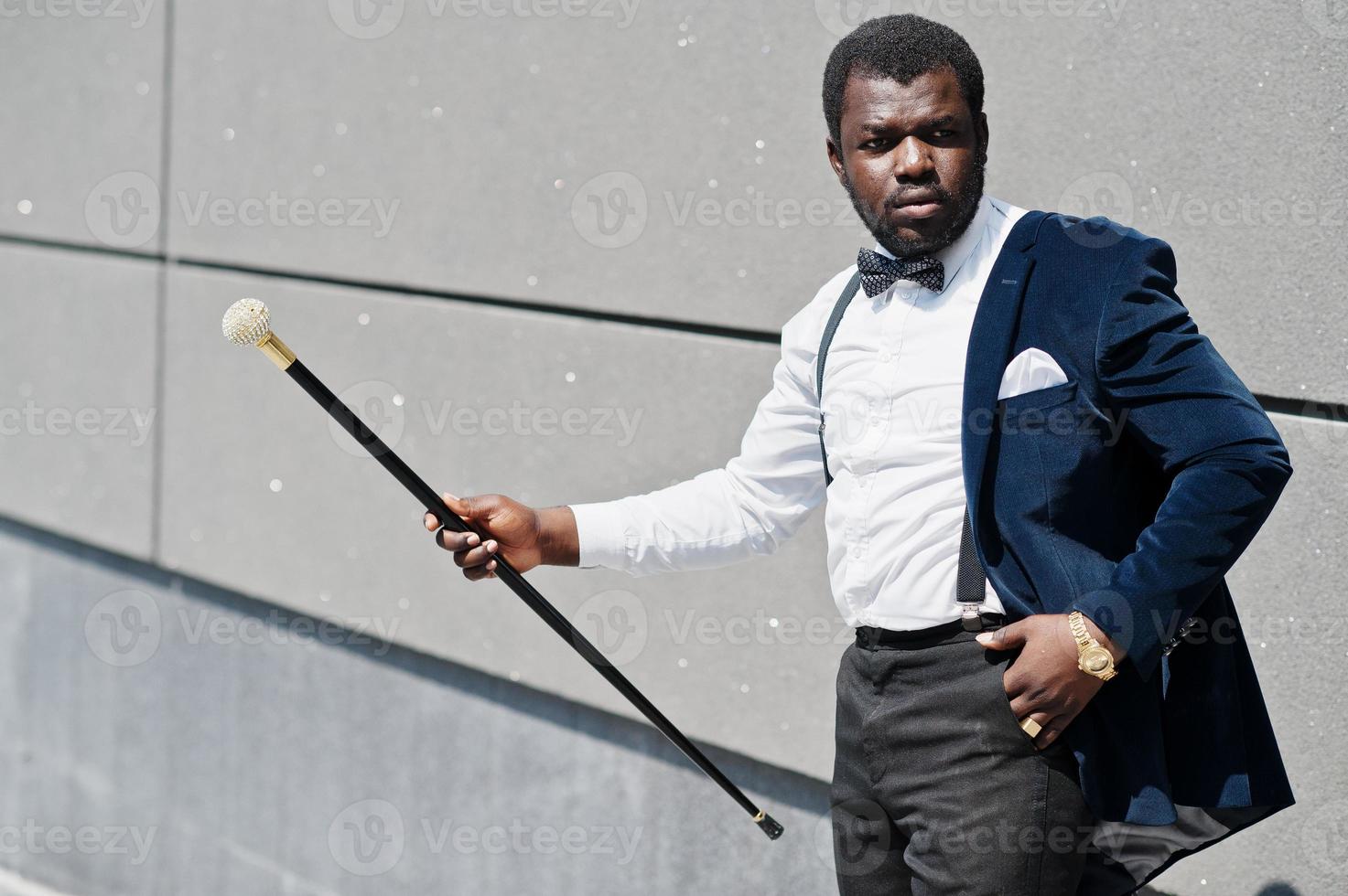 Handsome fashionable african american man in formal wear and bow tie with walking stick. photo