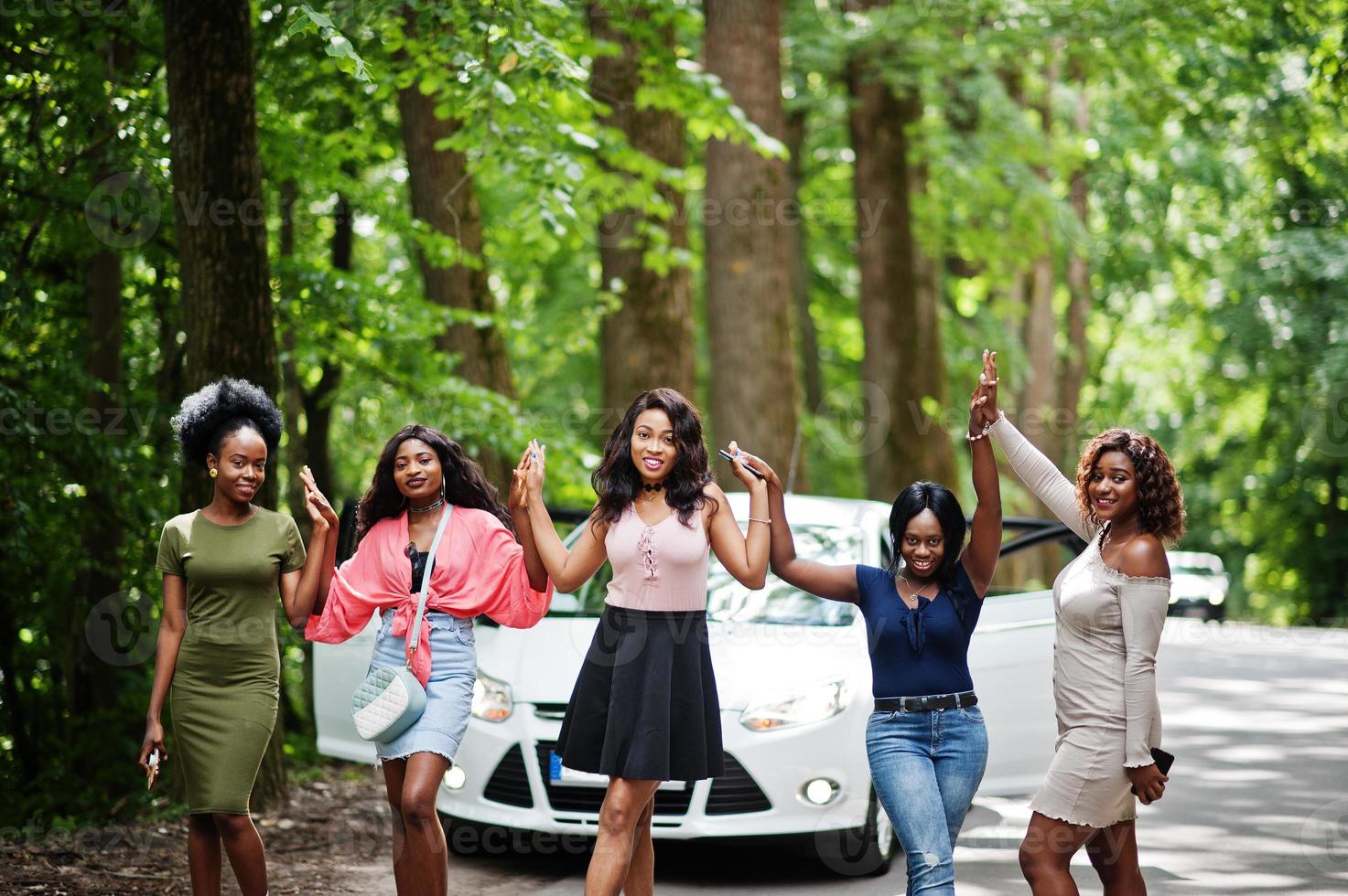 Group of five happy african american walking against white car. photo