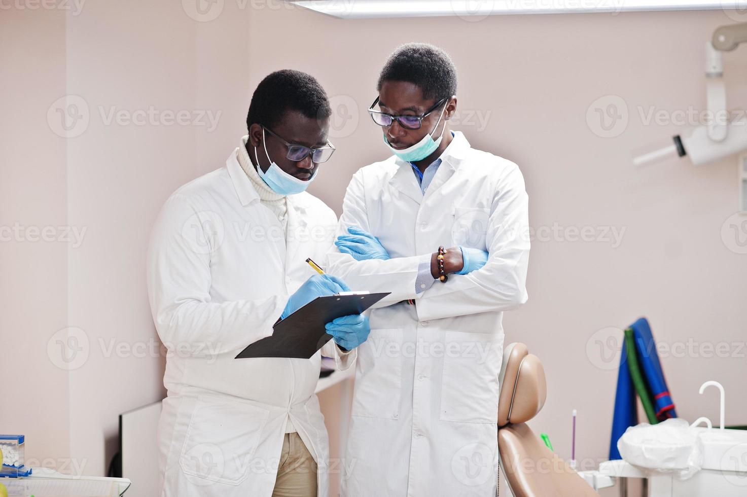 dos colegas médicos afroamericanos trabajando juntos, discutiendo y mirando el portapapeles en la clínica. foto