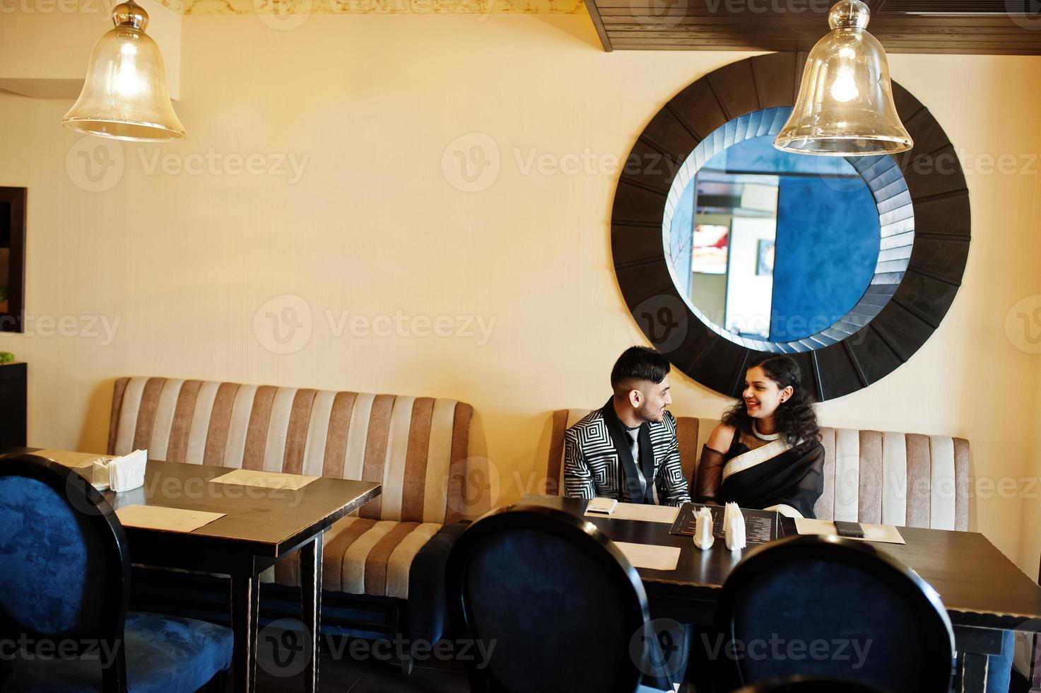 Lovely indian couple in love, wear at saree and elegant suit, posed on restaurant. photo