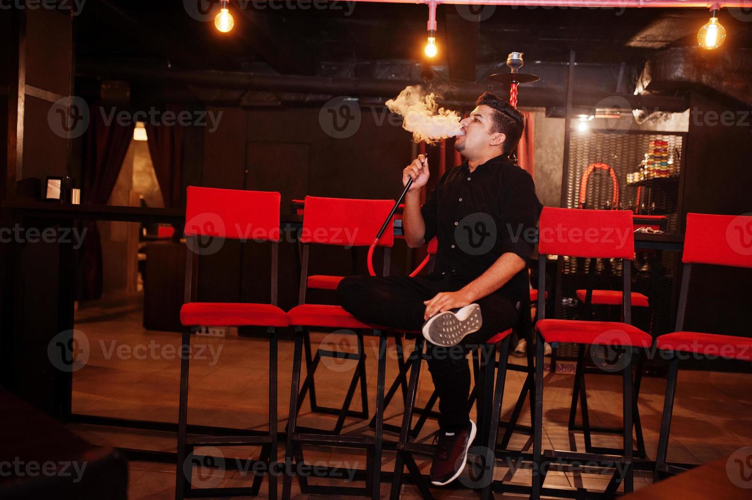 Asian man smoke hookah and having rest at lounge bar. photo