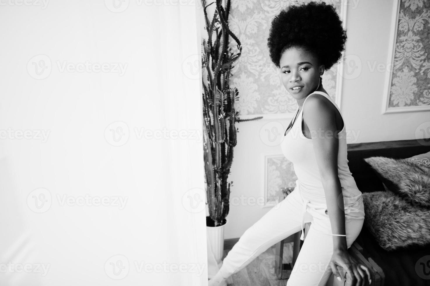 Young african american woman in pink singlet sitting at her room. photo