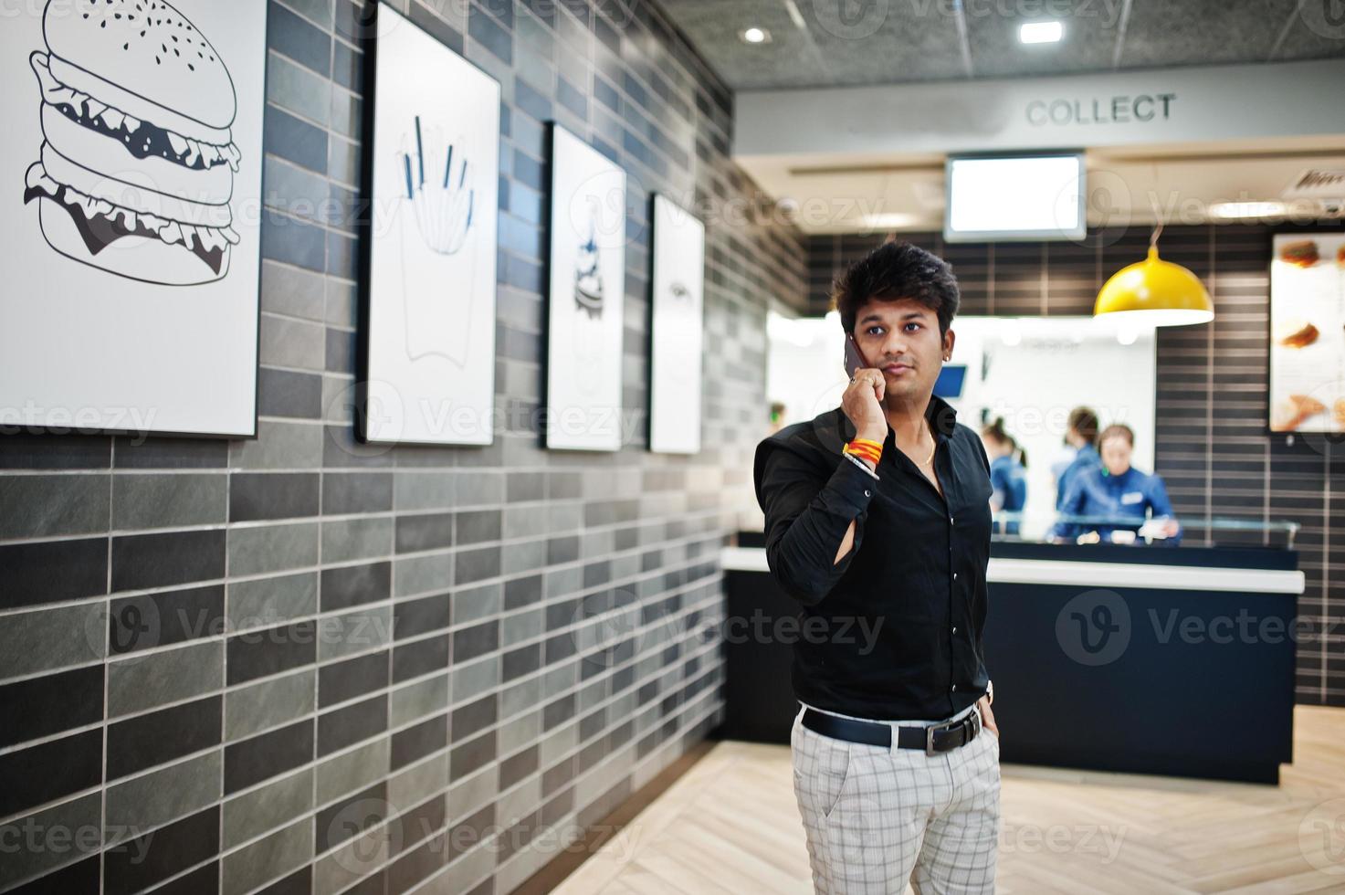 Indian man speaking on mobile phone while waiting for his order in the fast food cafe. photo