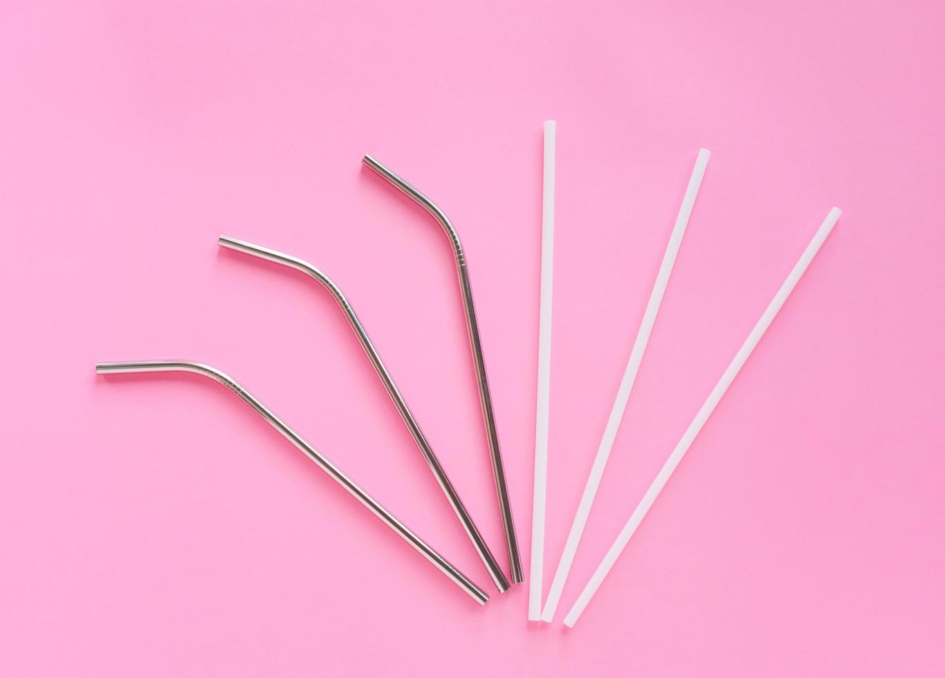 Flat lay of reusable stainless steel straw with plastic straw on bright pink color background, sustainable lifestyle and zero waste concept photo