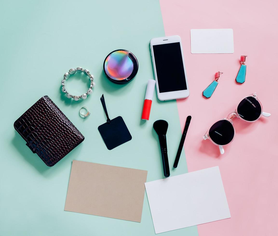 Flat lay of cosmetics, accessories, blank card and smartphone on pink and green background with copy space photo