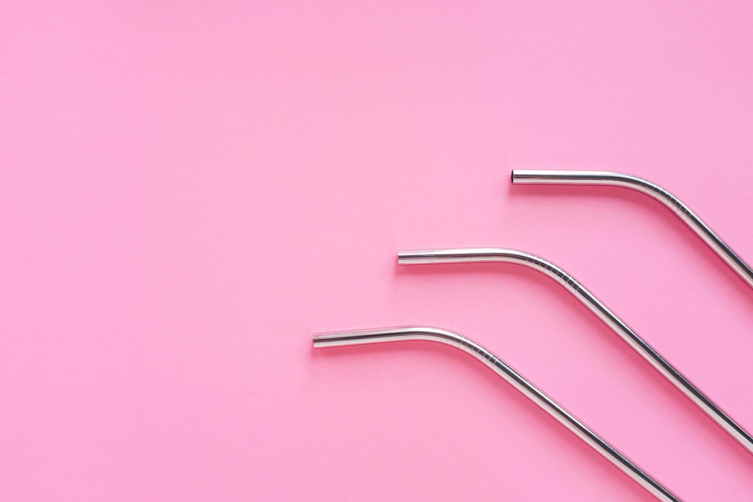 Flat lay of metallic stainless straws for drink on bright pink background, sustainable lifestyle and zero waste concept, copy space photo