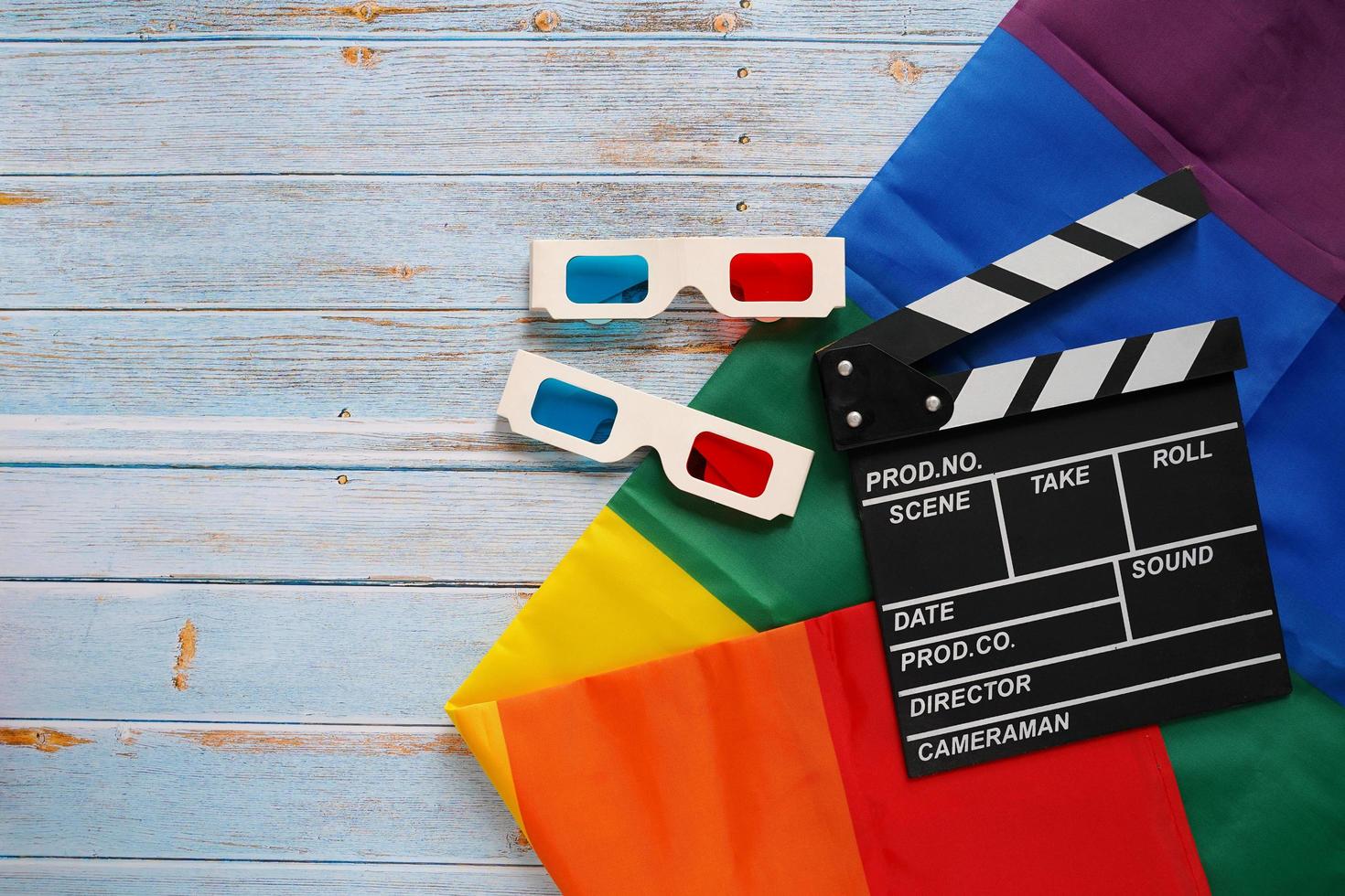 Flat lay of clapperboard and 3d glasses with LGBTQ flag on wooden background with copy space, pride movie industry photo