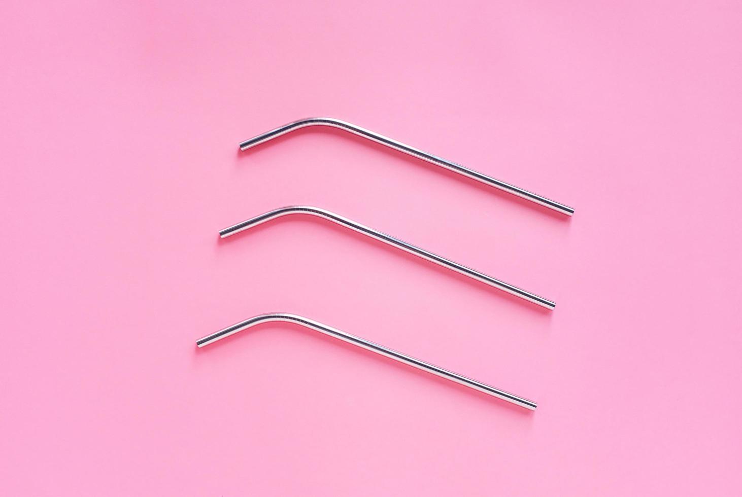 Flat lay of metallic stainless straws for drink on bright pink background, sustainable lifestyle and zero waste concept photo