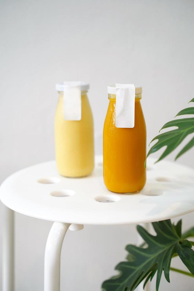 Cold pressed juice of pumpkin and pineapple in bottle mockup with blank label for healthy drink with vitamin and antioxidant, vegan lifestyle photo