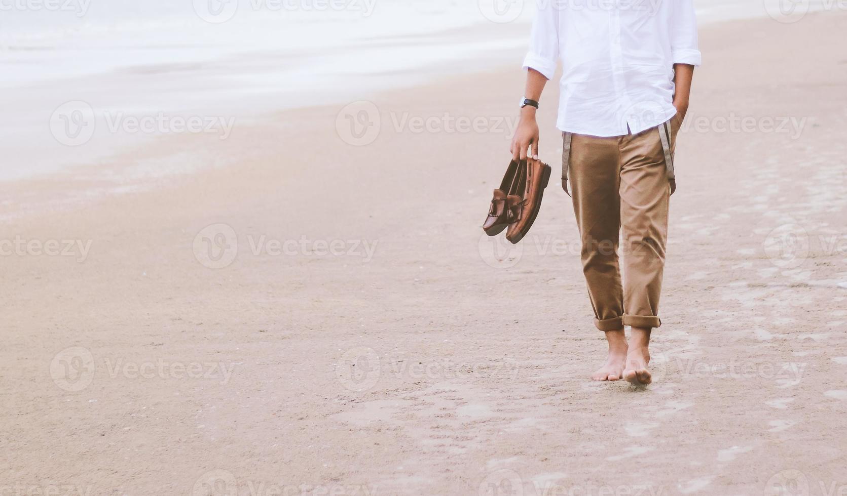 hombre solo caminando por la playa con zapatos de cuero foto