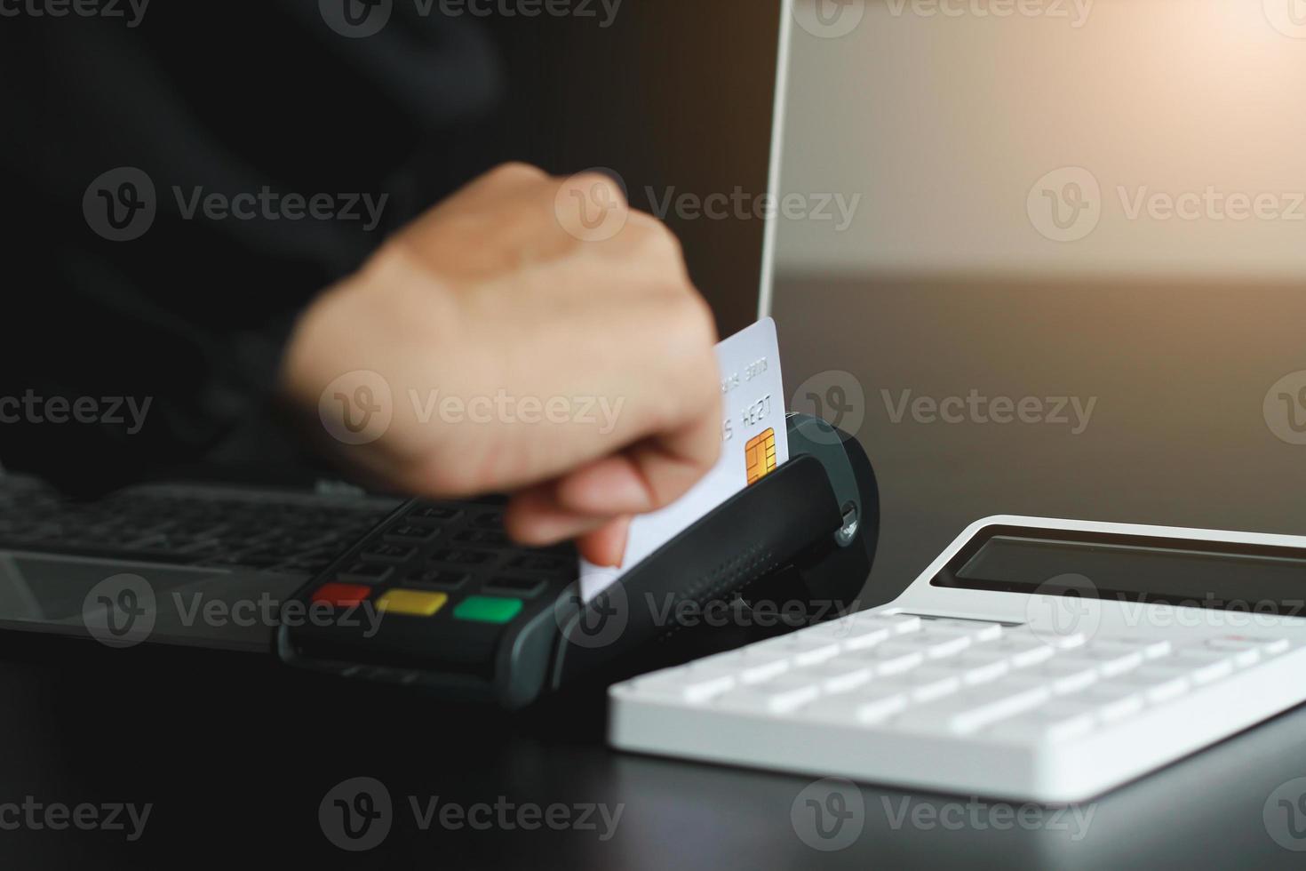 A woman using hand credit card swipe machine for sell products in the shop. Concept of spending via credit card. photo