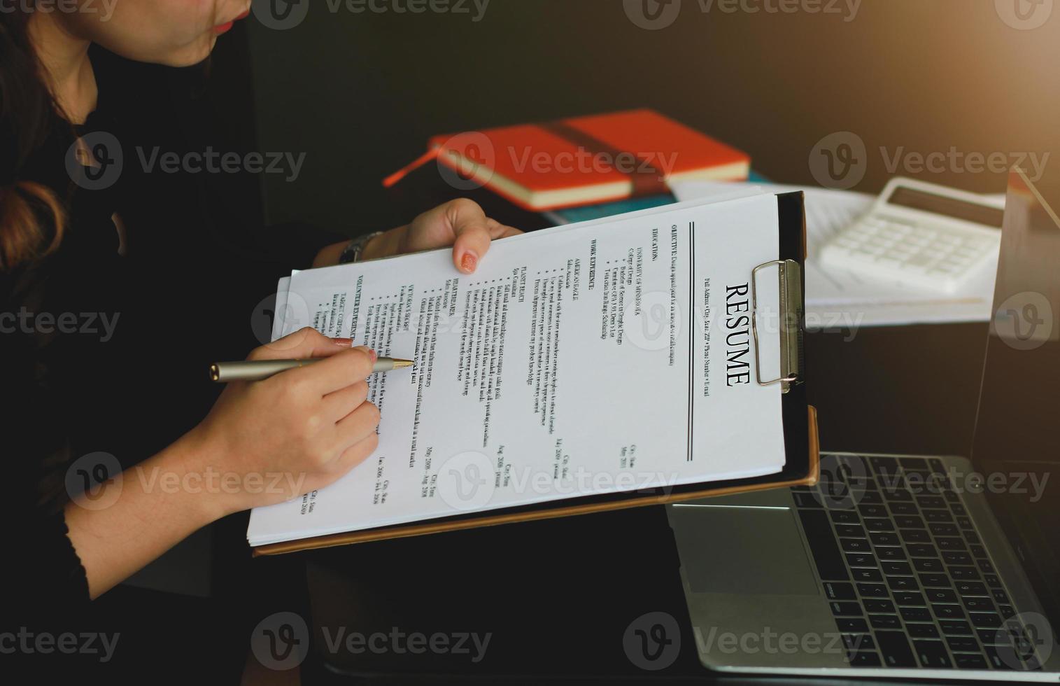 Close-up of a businessman holding a resume and reviewing his resume on a desk with a laptop computer and calculator. photo