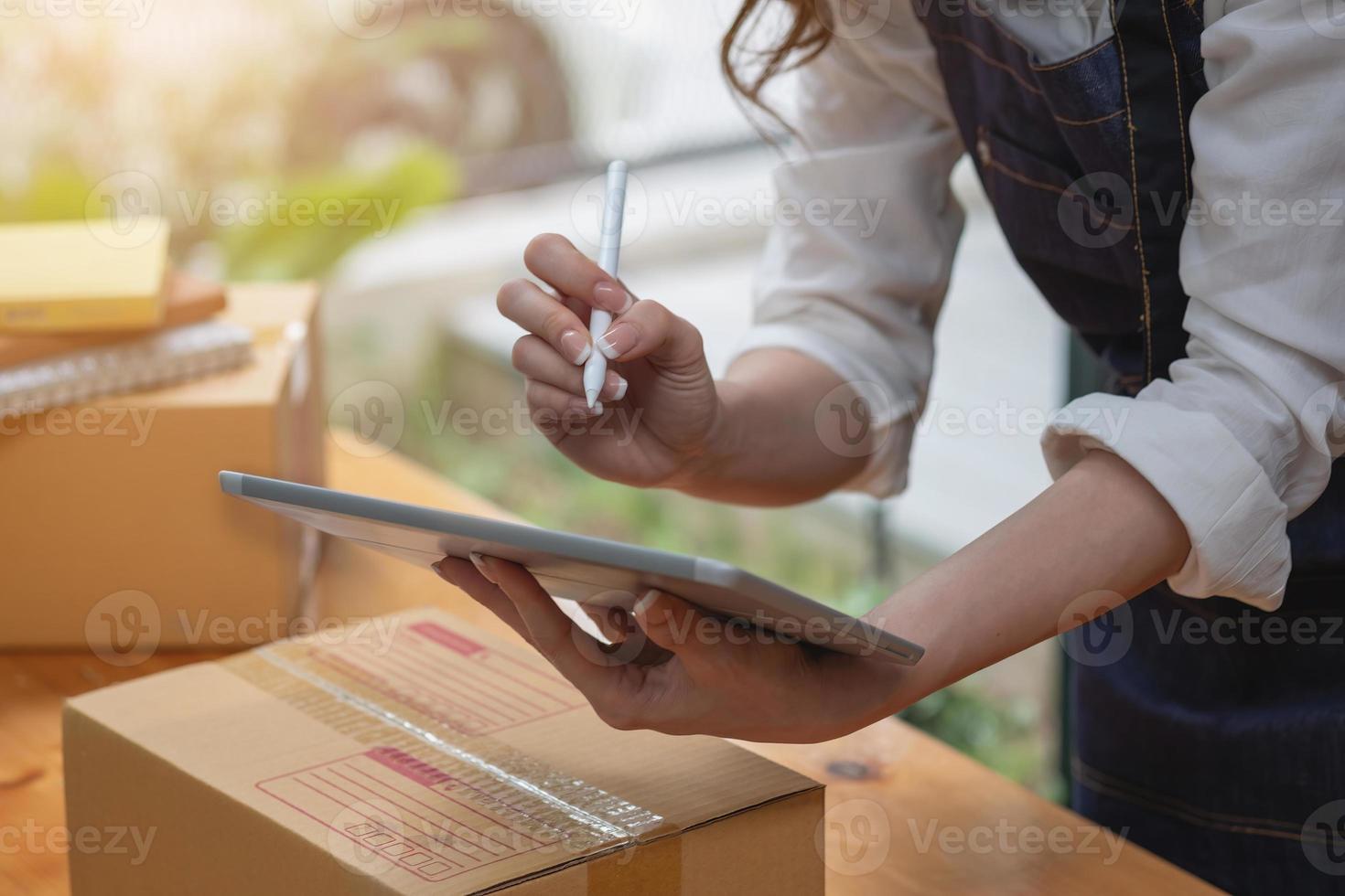 La propietaria de una empresa de ventas en línea recibe pedidos y entrega productos con cajas a los clientes. concepto de negocio de pymes en línea. foto