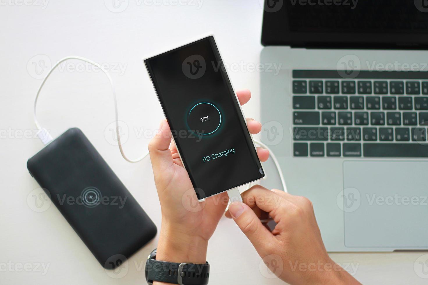 Close up Man holding smartphone charging battery from Power Bank type c port with using pd charging technology. photo