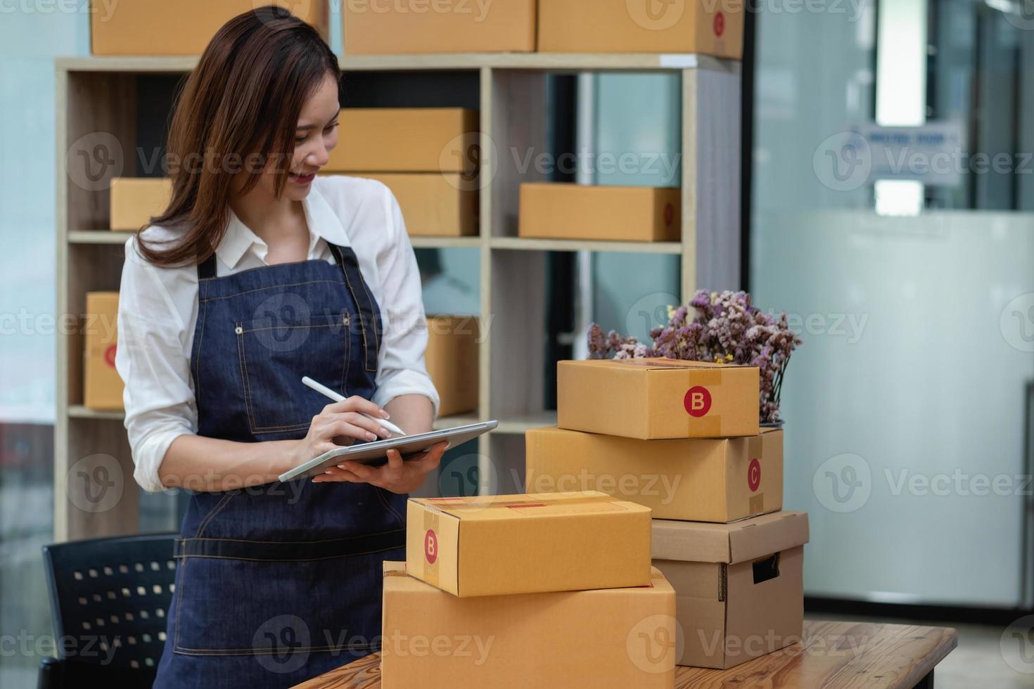 La propietaria de una empresa de ventas en línea recibe pedidos y entrega productos con cajas a los clientes. concepto de negocio de pymes en línea foto