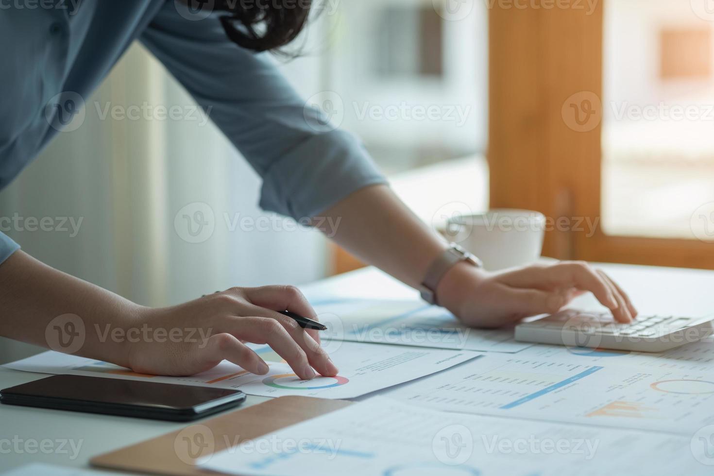 Portrait of a female accountant using a calculator and laptop to calculate balance using graphs for customers. photo