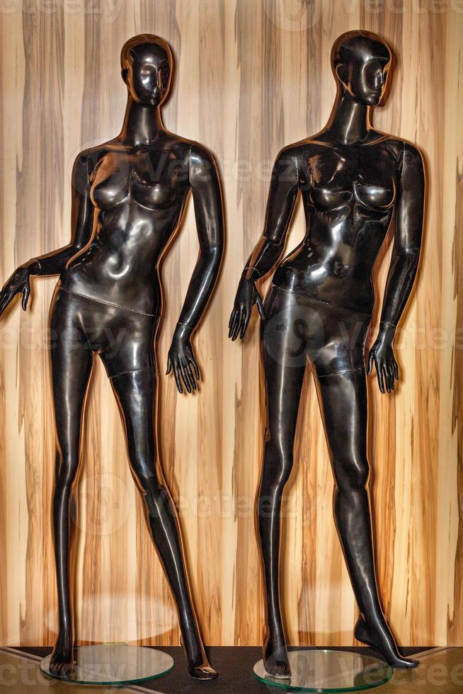 Two black mannequins on a wooden background for displaying clothes in a store. photo