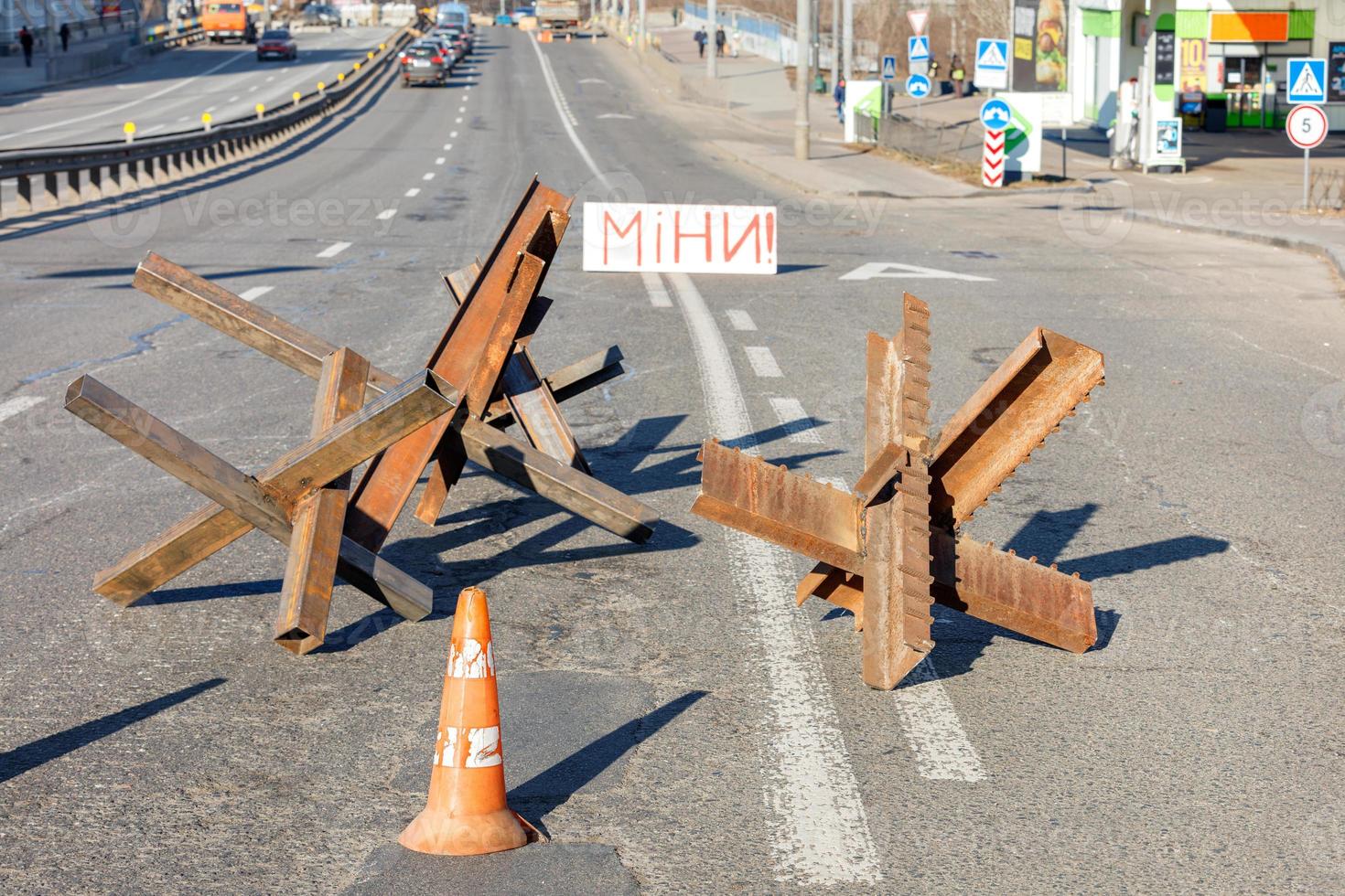 Protective anti-tank metal welded hedgehogs on the carriageway of the city road and the inscription Mines on a sunny day. 28.02.22. Ktiv. Ukraine. photo