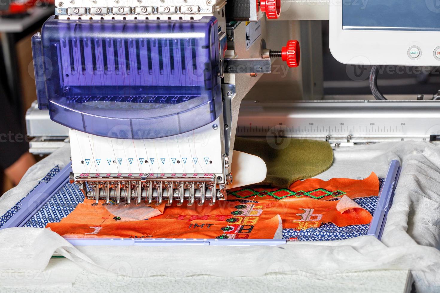 Computerized industrial embroidery machine with multicolored threads, close-up, selective focus. photo