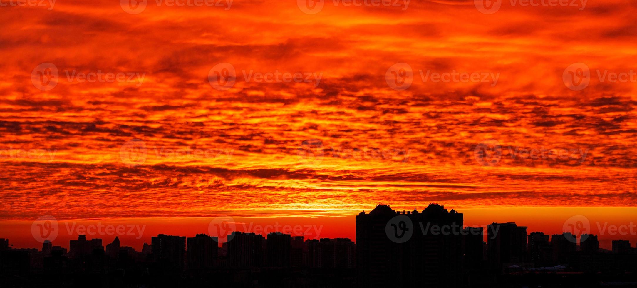 The black outline of the city at night against the backdrop of a bloody sunrise in the early morning. photo