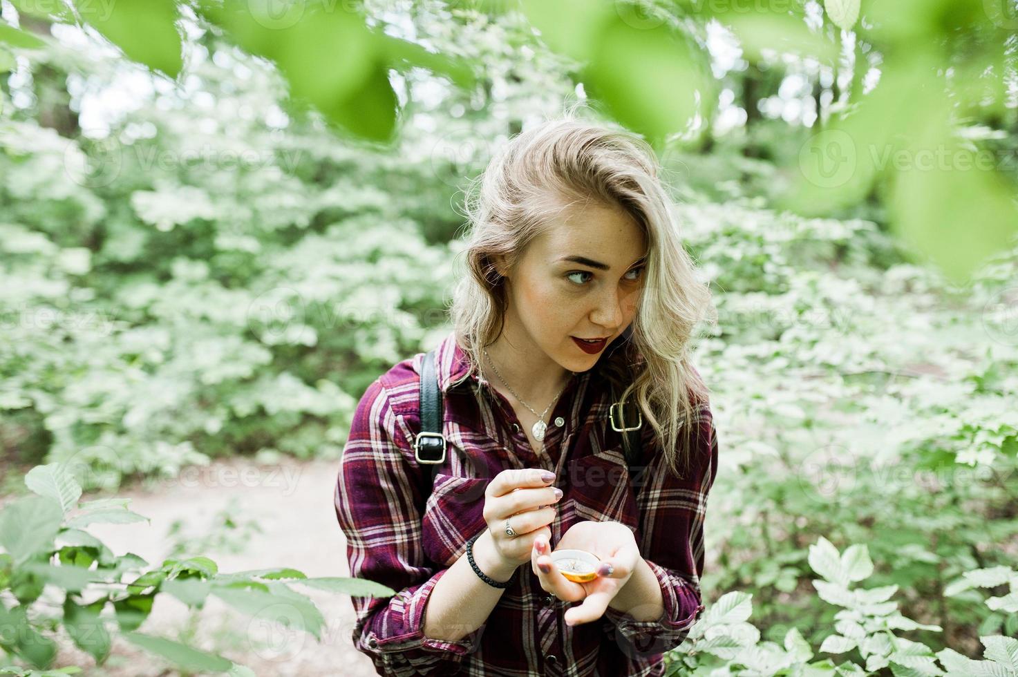 Portrait of an attractive blond girl posing with a compass in a forest. photo