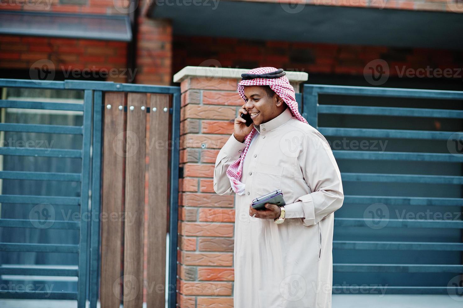 Middle Eastern arab business man posed on street against modern building with tablet and mobile phone at hands. photo