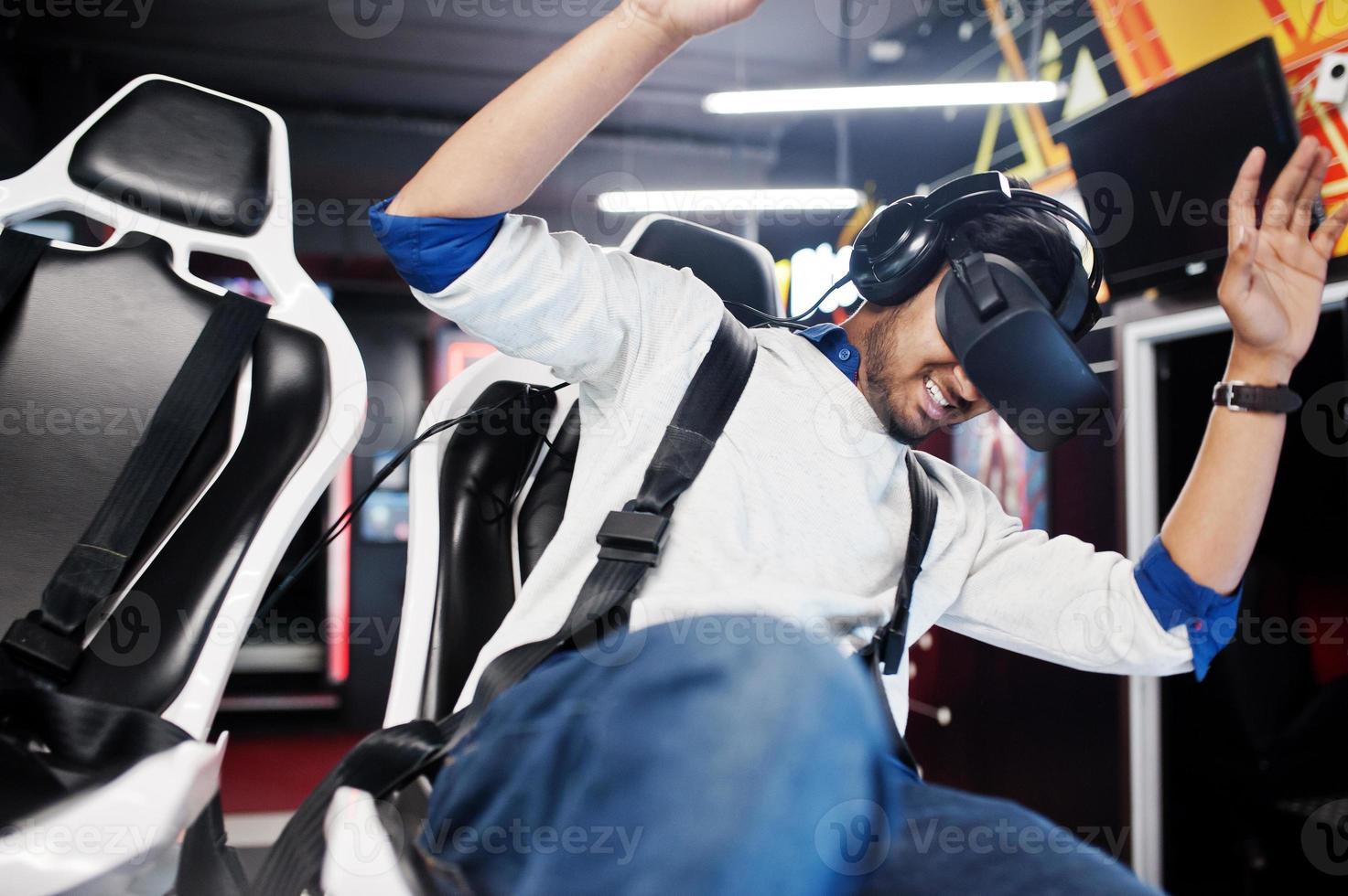 Young indian man having fun with a new technology of a vr headset at virtual reality simulator. photo