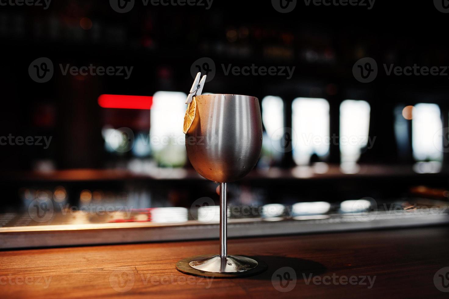 Alcoholic cocktail with ice in silver glass on bar table. photo