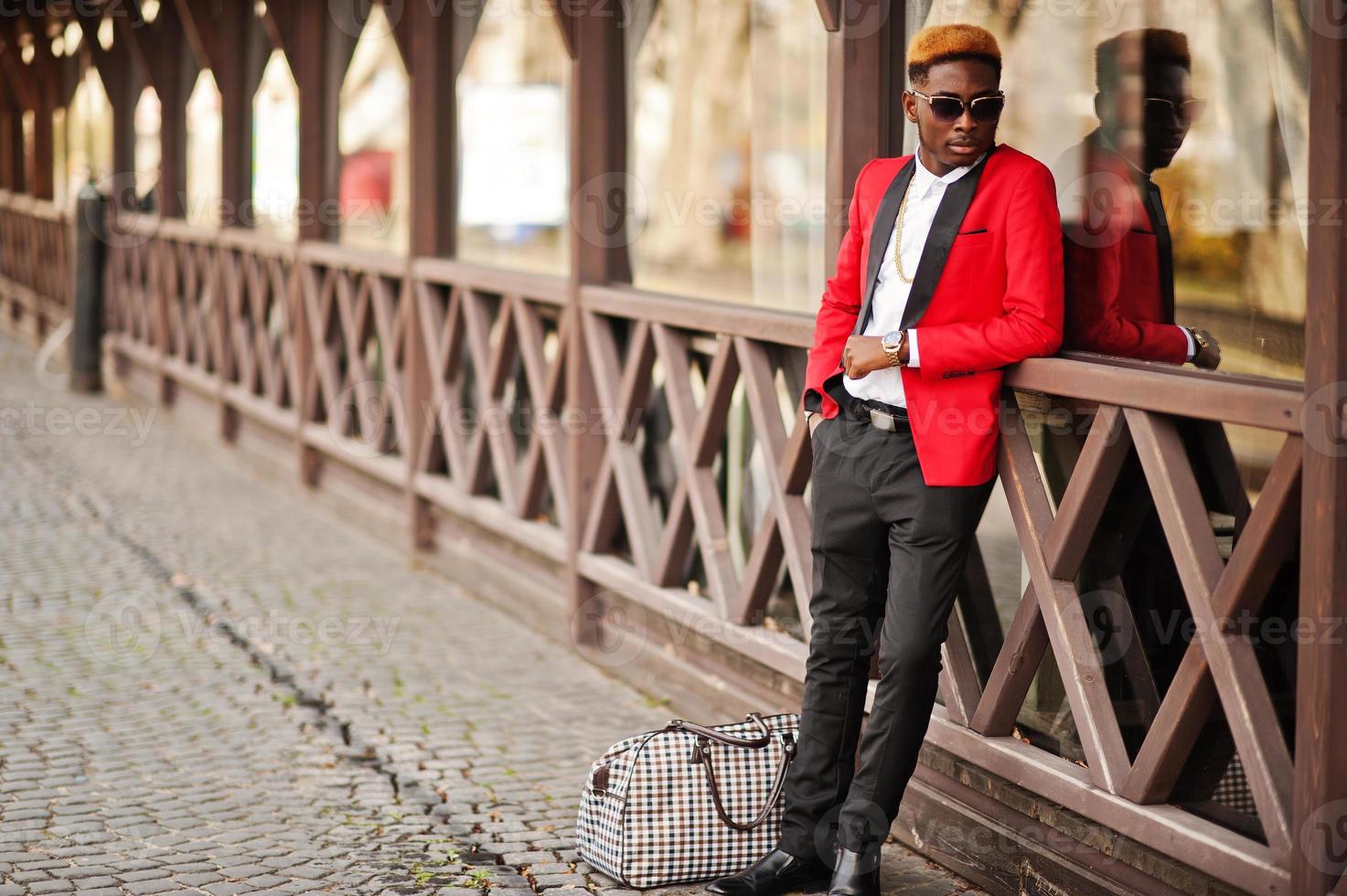 Fashion african american man model at red suit, with highlights hair and handbag posed at street. photo