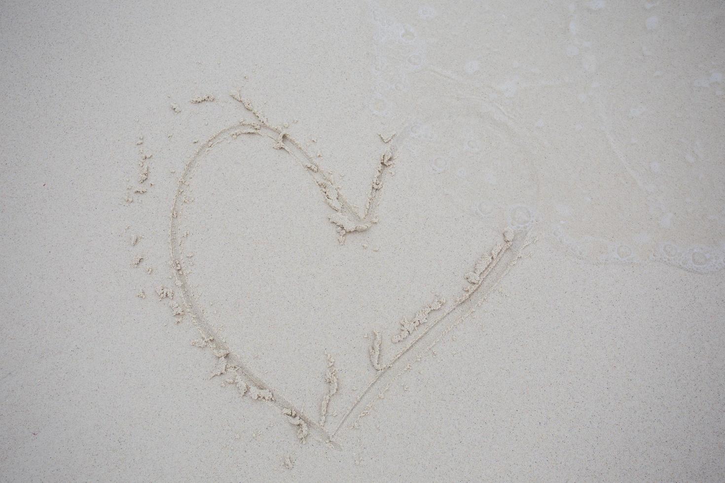 corazones dibujados en la arena de una playa foto