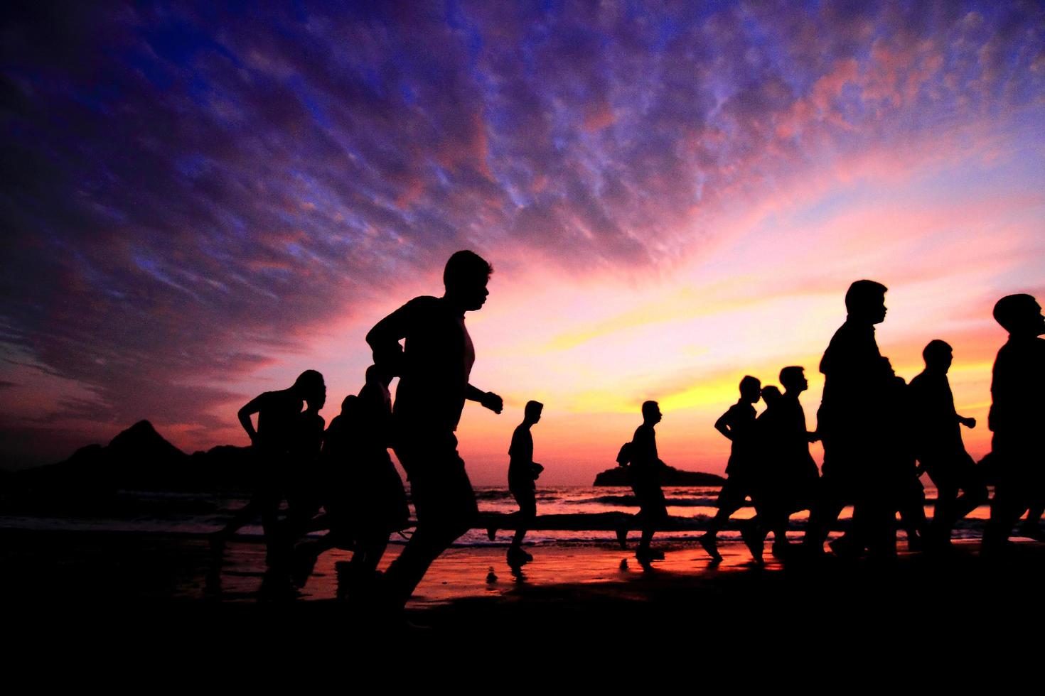 grupo de jóvenes corre en la playa en la hermosa puesta de sol de verano foto