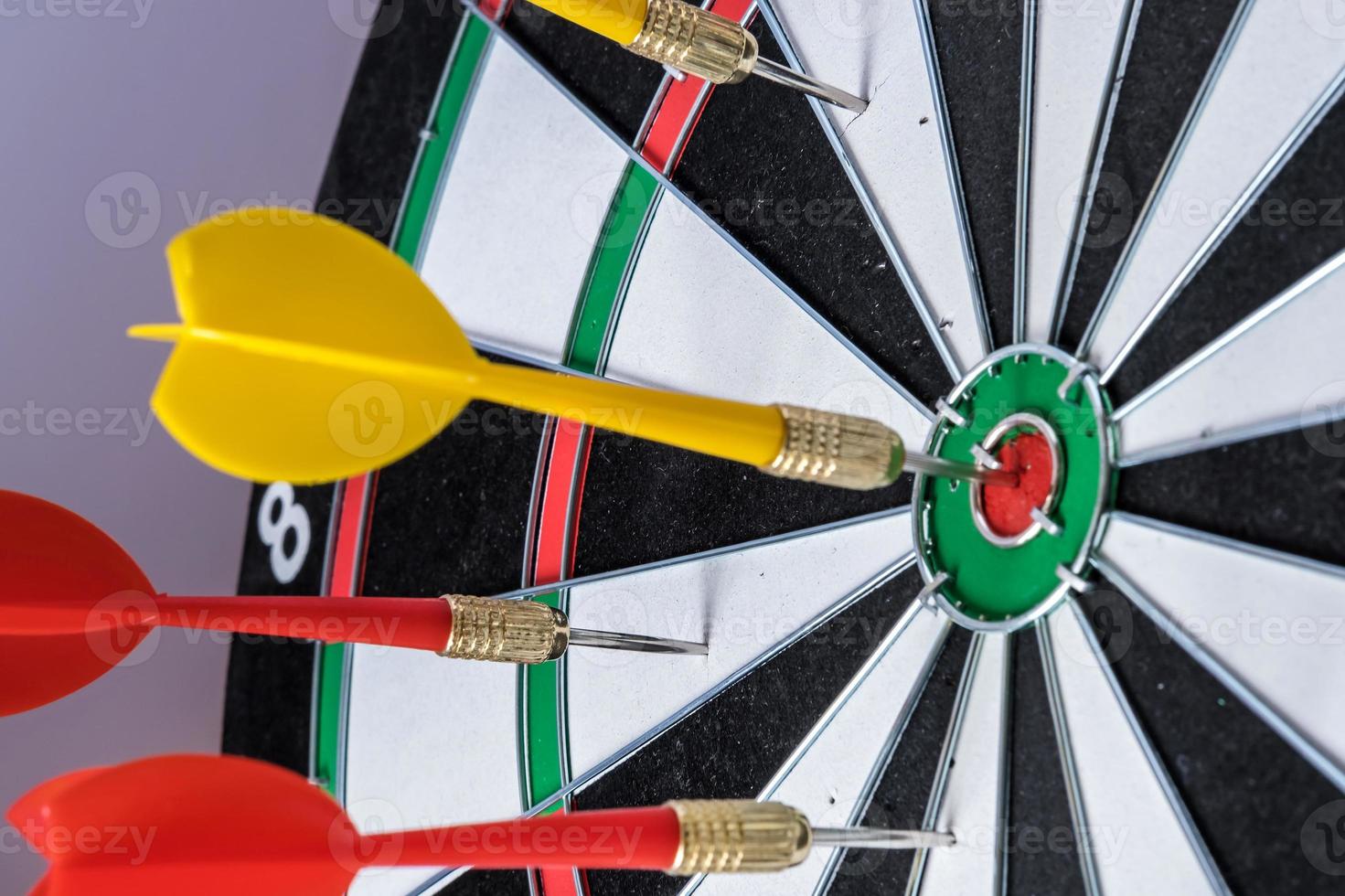 Red and yellow dart arrows hitting in the target center of dartboard. Success hitting target aim goal achievement concept photo