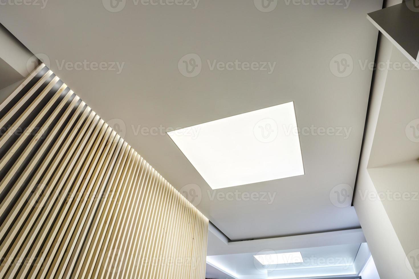 halogen spots lamps on suspended ceiling and drywall construction in in empty room in apartment or house. Stretch ceiling white and complex shape. photo