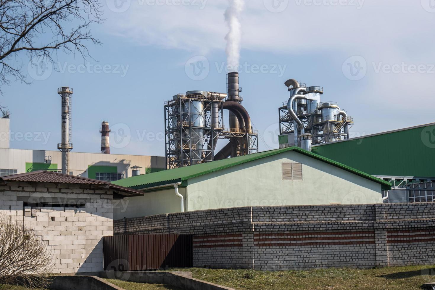 tuberías del aserradero de la planta de la empresa de carpintería cerca del río. concepto de contaminación del aire. paisaje industrial contaminación ambiental residuos de central térmica foto