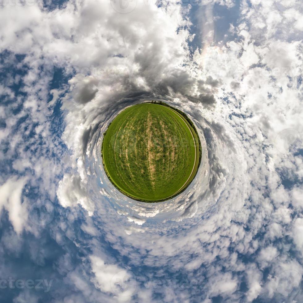 Little planet transformation of spherical panorama 360 degrees. Spherical abstract aerial view in field with awesome beautiful clouds. Curvature of space. photo