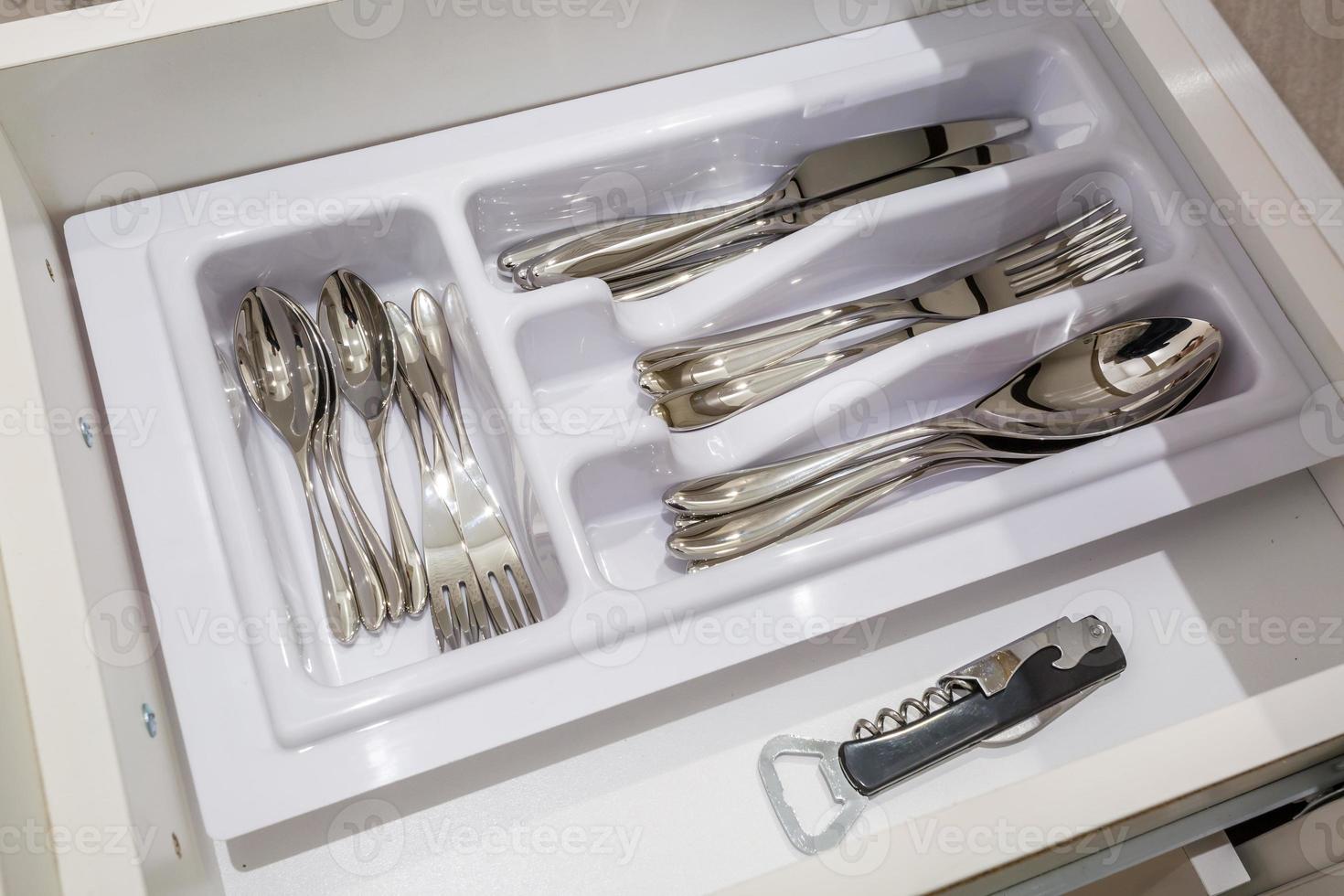 cutlery spoons forks knives and tea spoon on the shelf in the kitchen cupboard photo