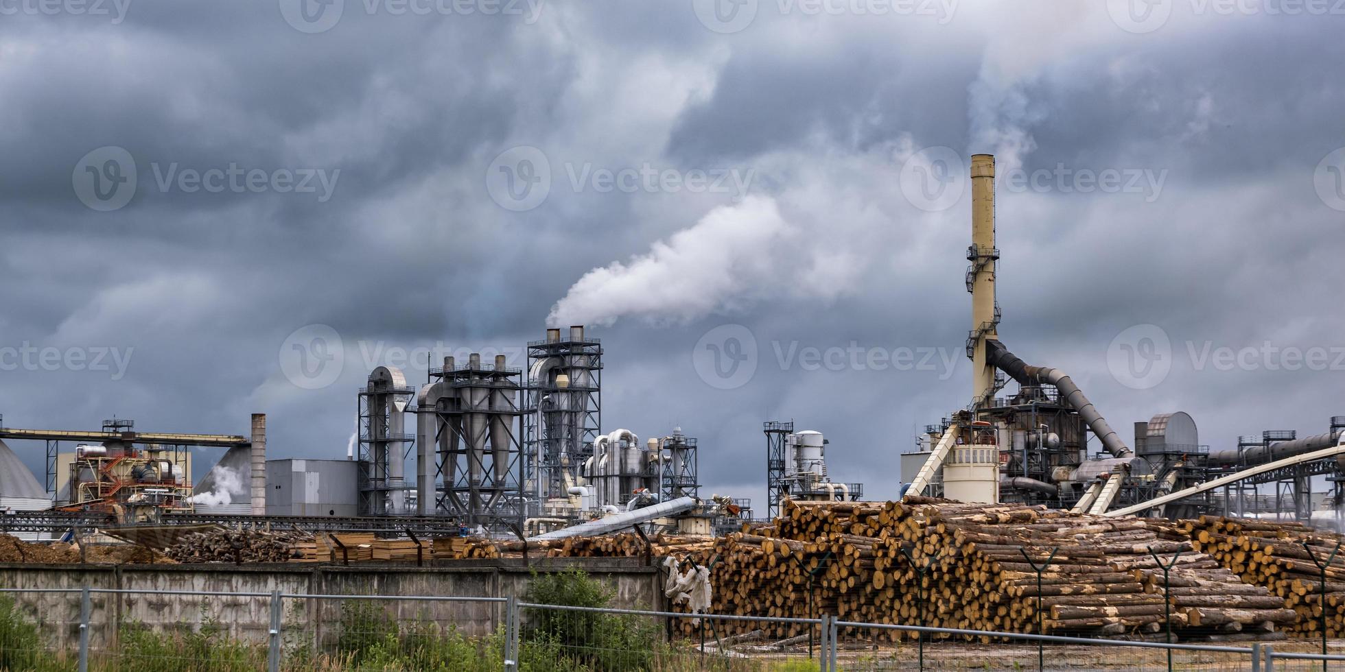 tuberías del aserradero de la planta de la empresa de carpintería contra un cielo gris sombrío. concepto de contaminación del aire. panorama del paisaje industrial contaminación ambiental residuos de la central térmica foto