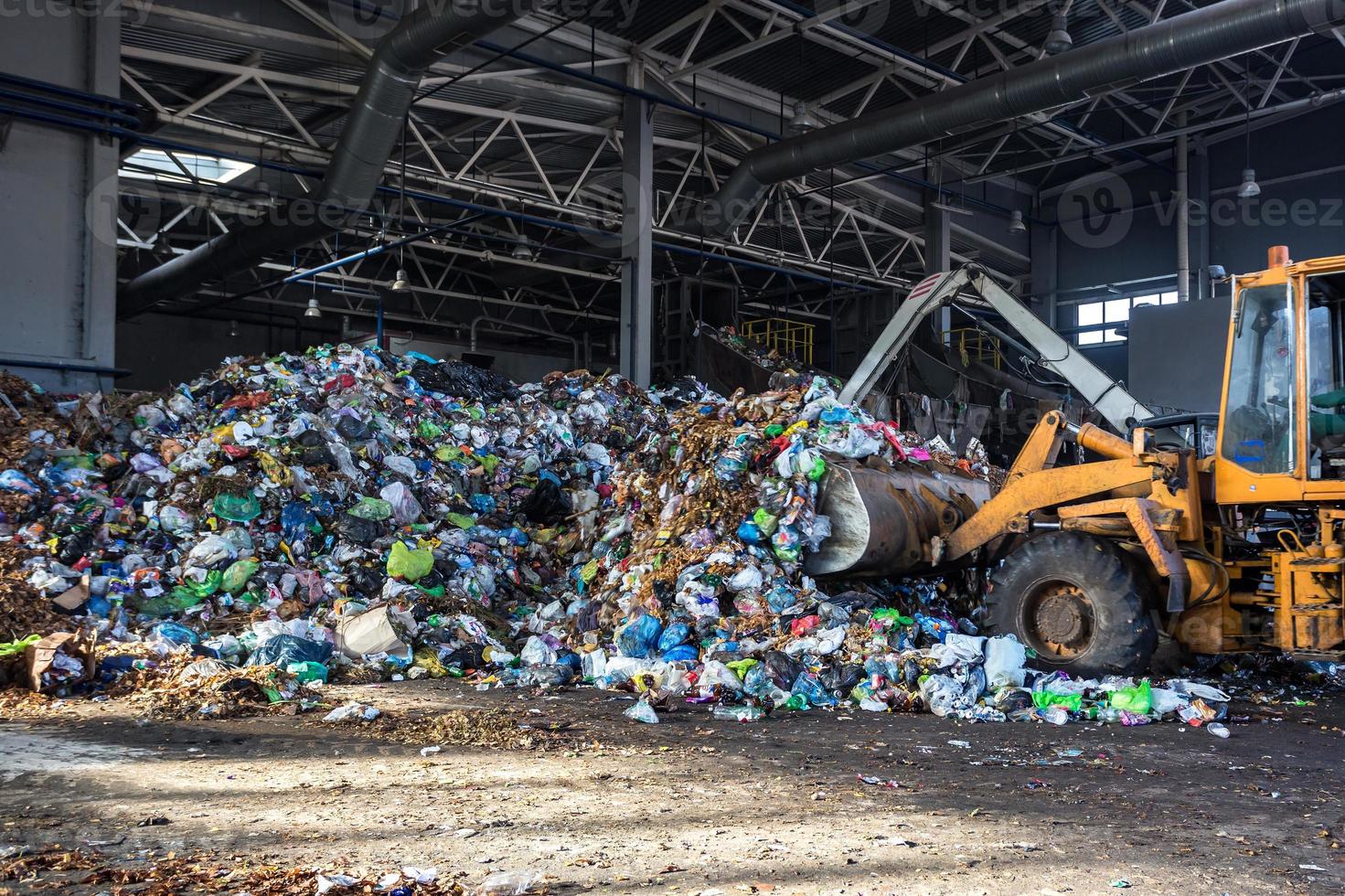 la excavadora apila basura en una gran pila en la clasificación de la moderna planta de procesamiento de reciclaje de residuos. separación y clasificación de la recolección de basura. reciclaje y almacenamiento de residuos foto