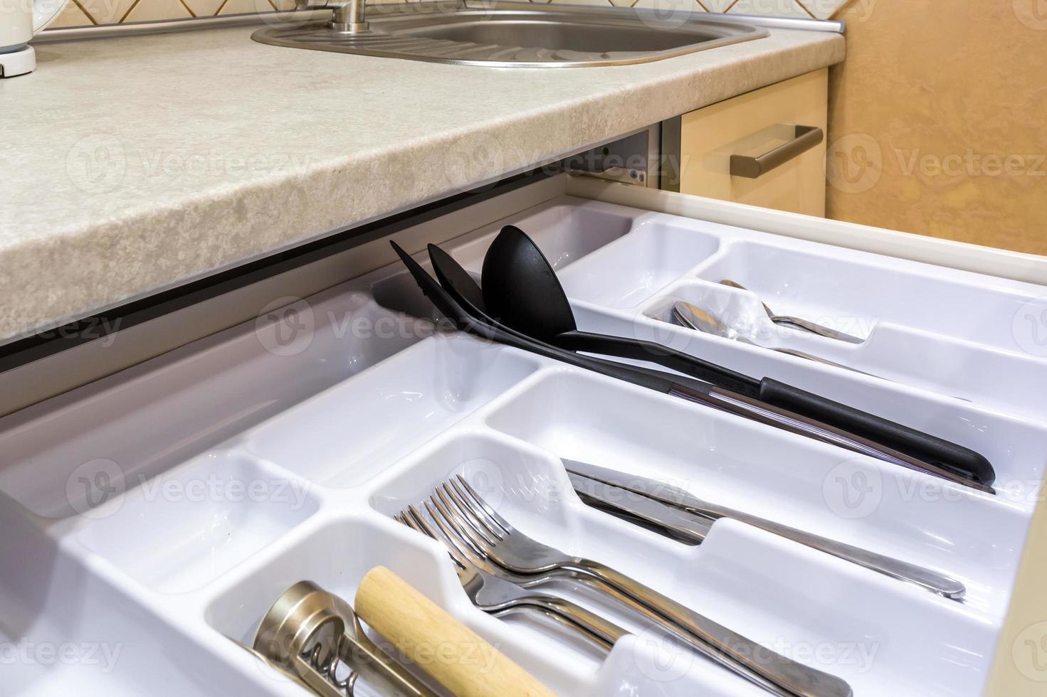 cutlery spoons forks knives and tea spoon on the shelf in the kitchen cupboard photo