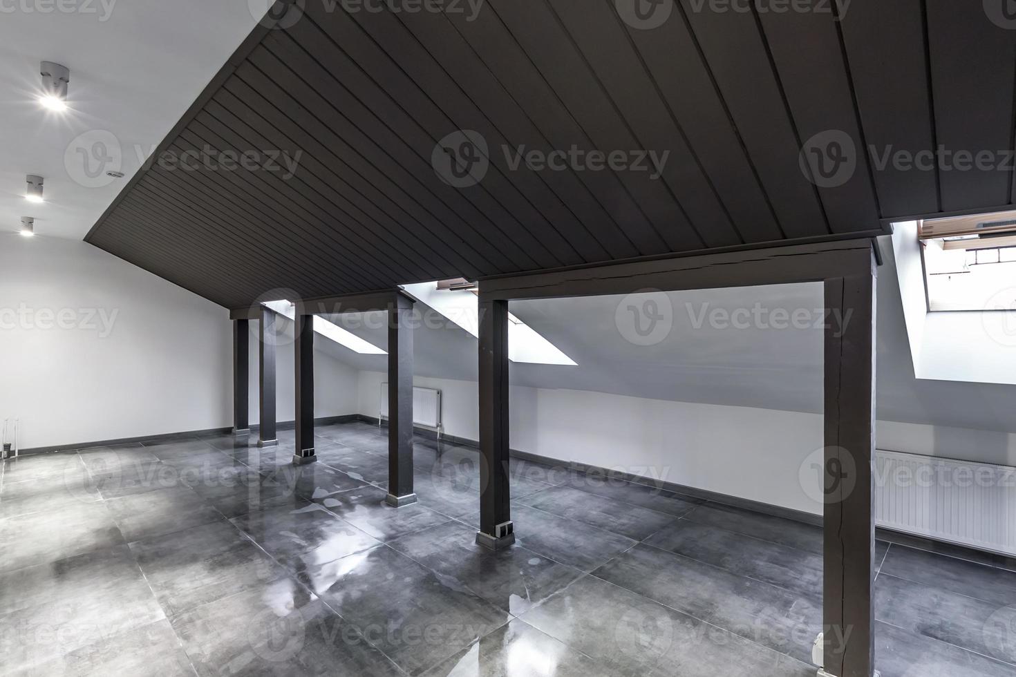 Empty unfurnished loft mansard room interior with wooden columns and wet concrete floor on roof level in black and whote style color photo