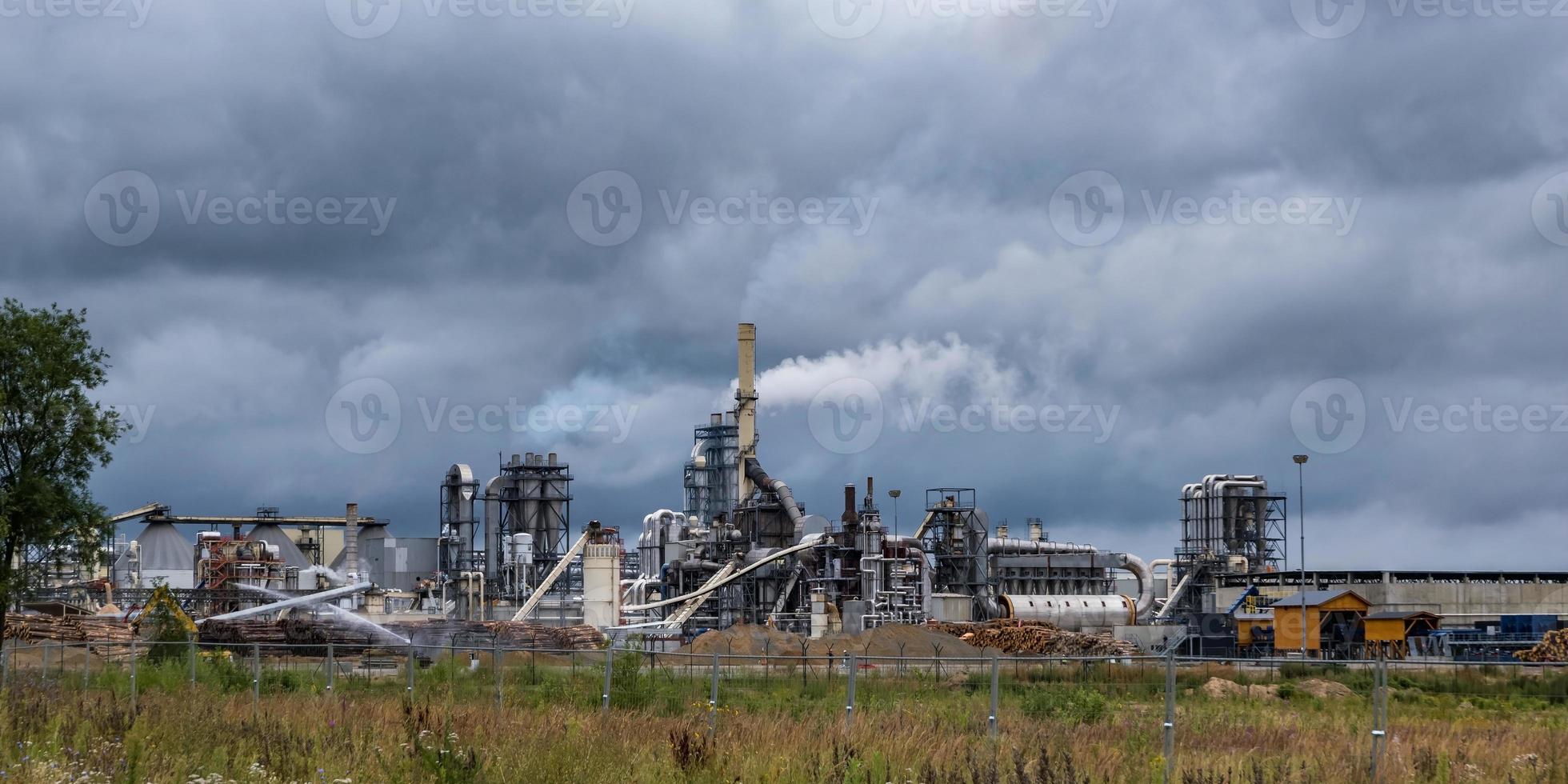 tuberías del aserradero de la planta de la empresa de carpintería contra un cielo gris sombrío. concepto de contaminación del aire. panorama del paisaje industrial contaminación ambiental residuos de la central térmica foto