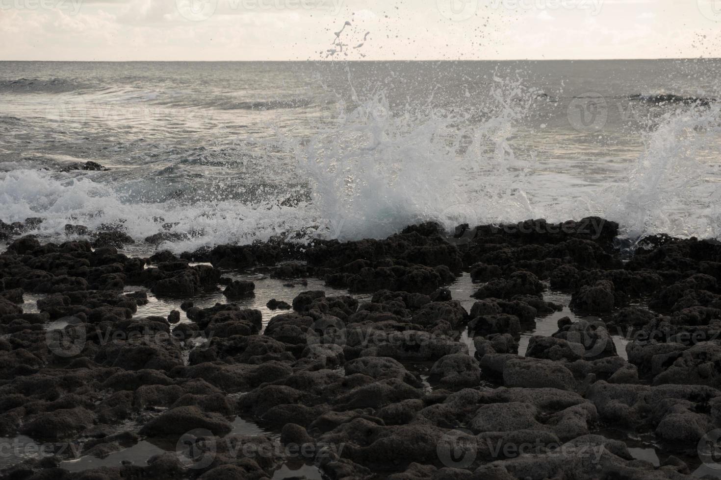 Ocean wave splashing over the stones photo