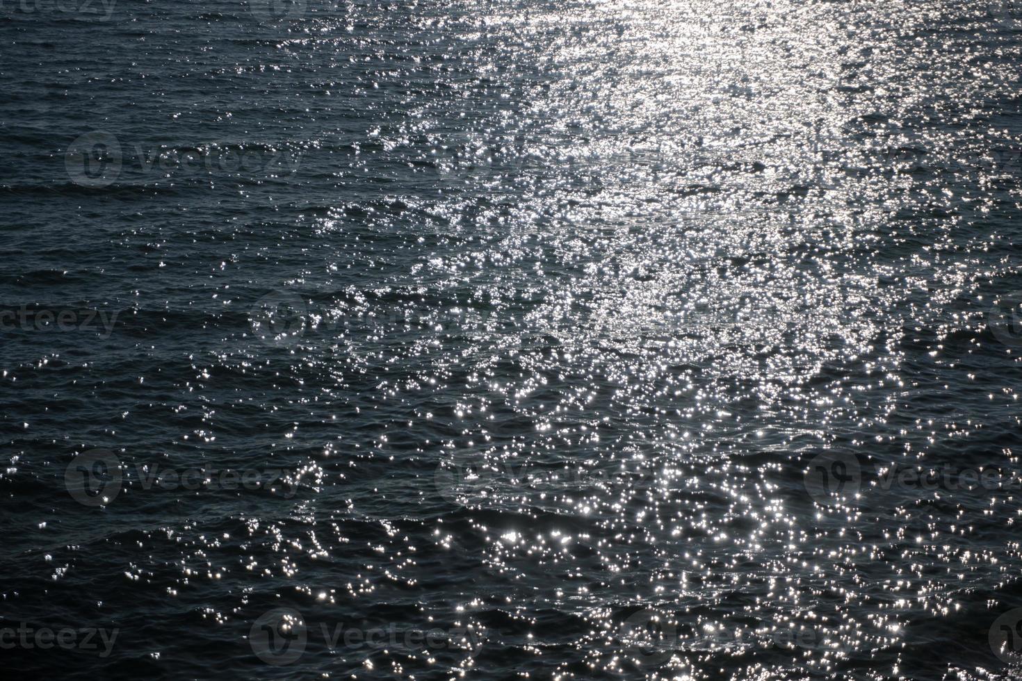 Sea water surface with ripple and sun reflection sparkles photo